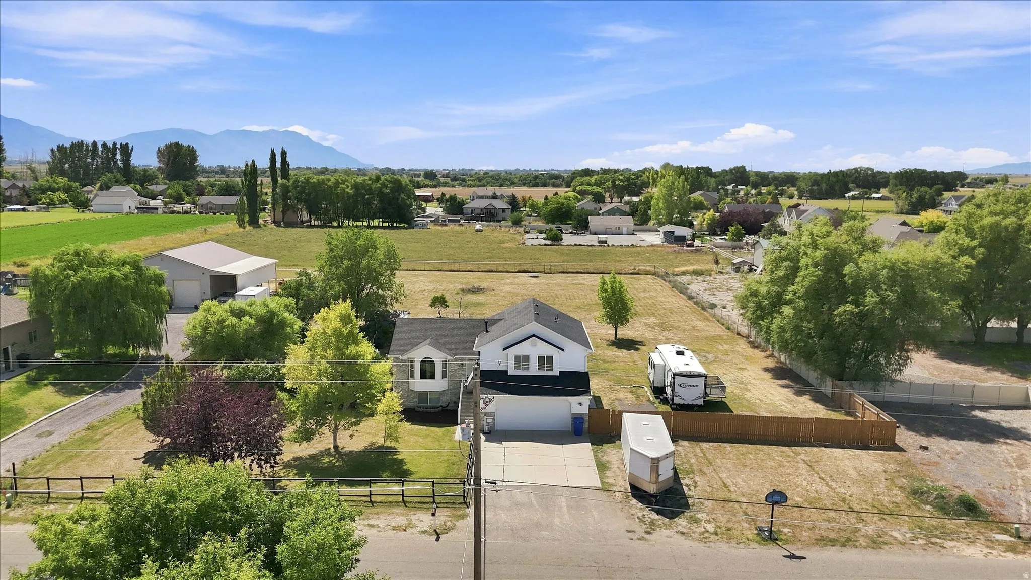 Expansive property featuring a two-story residence with a two-car garage, mature landscaping, and a fenced yard