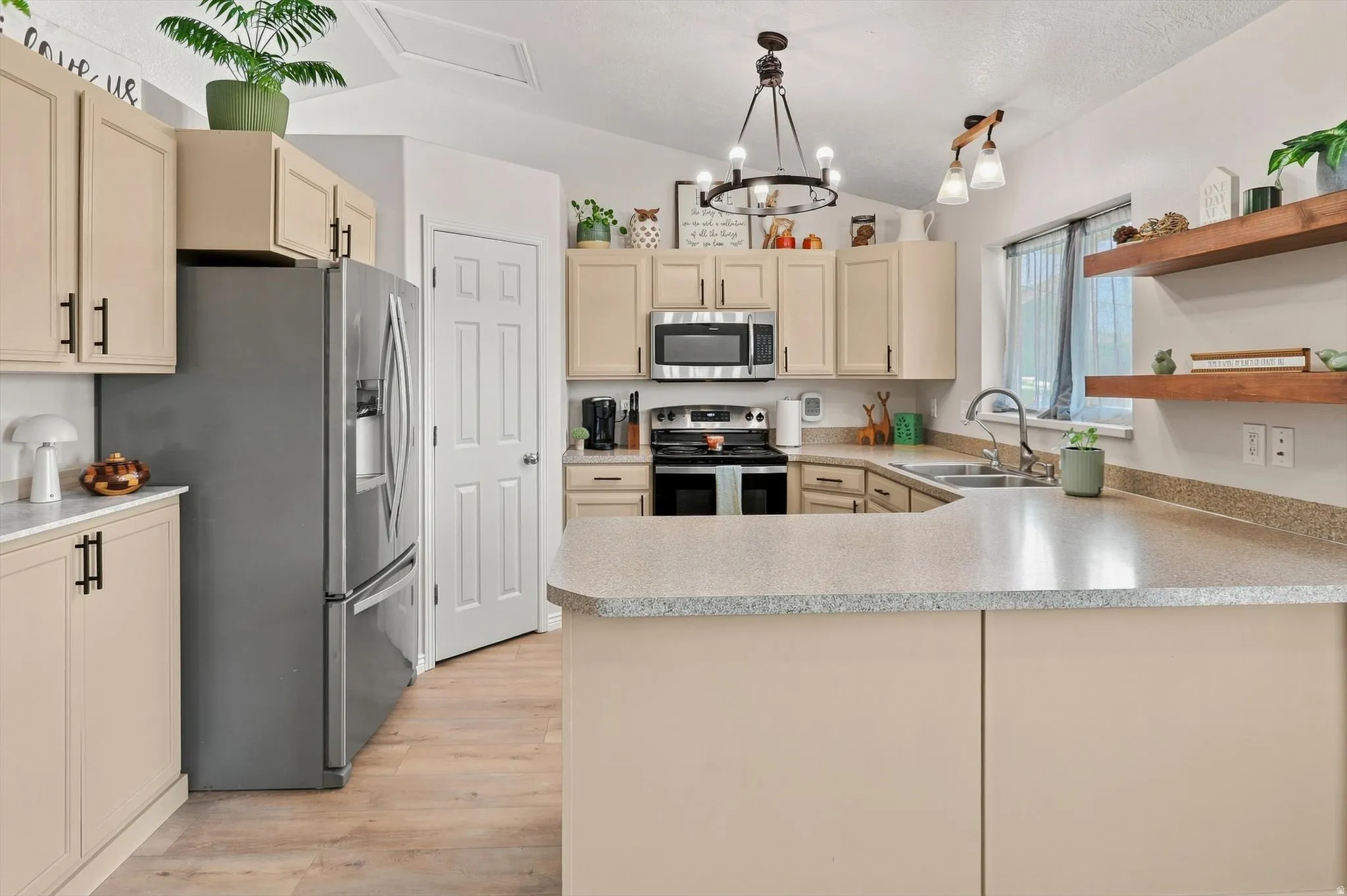 Kitchen featuring a U-shaped countertop configuration, light-toned cabinetry with dark hardware, and stainless steel appliances