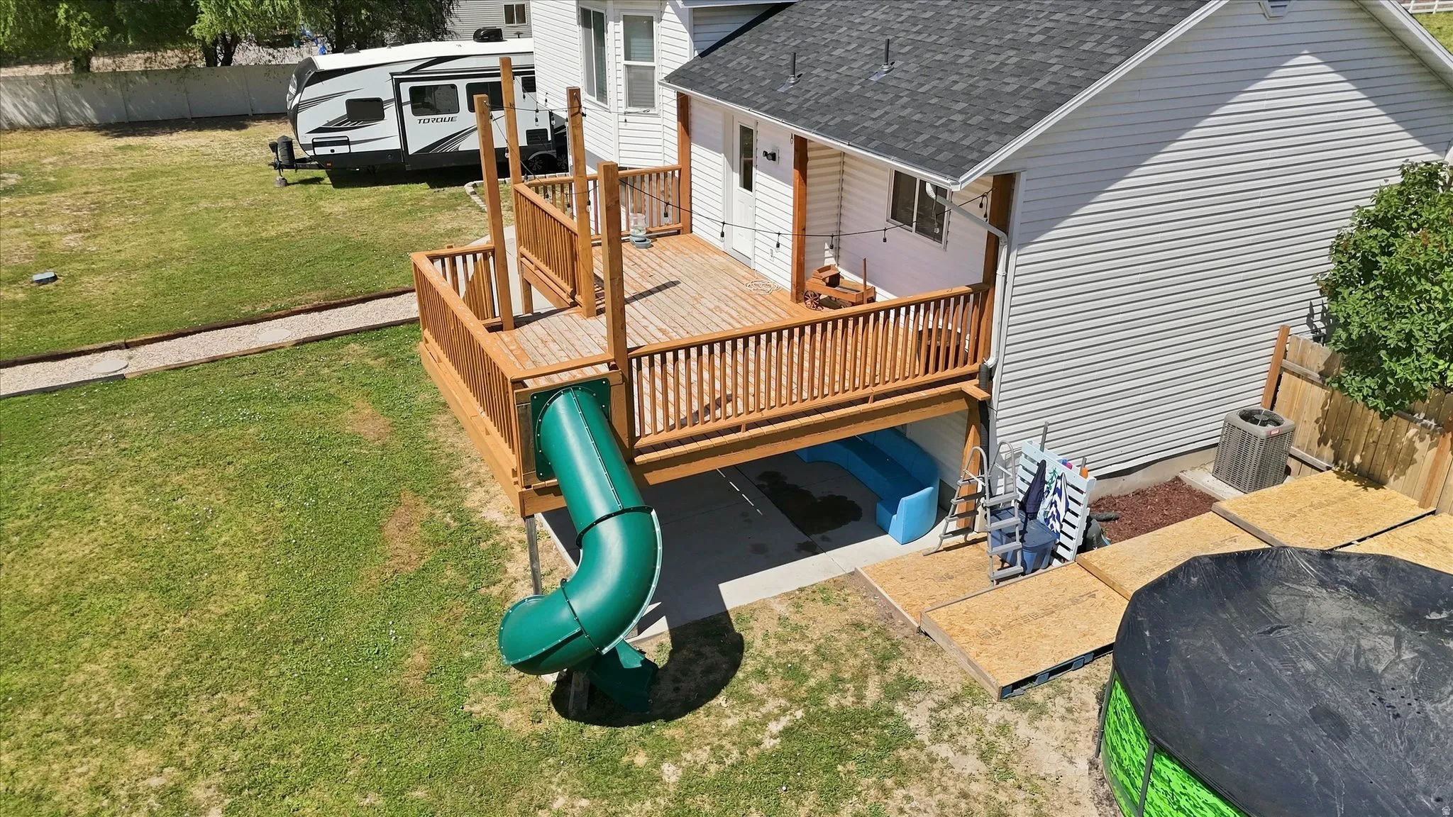 Wood-finish deck with railing, integrated slide, and covered patio area