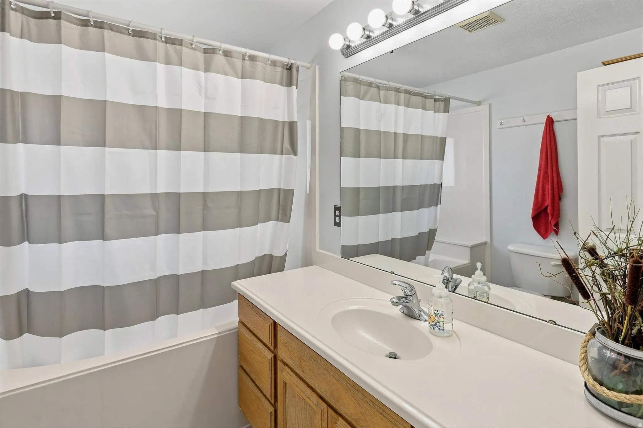Built-in vanity with light-toned countertop, undermount sink, and wood cabinetry