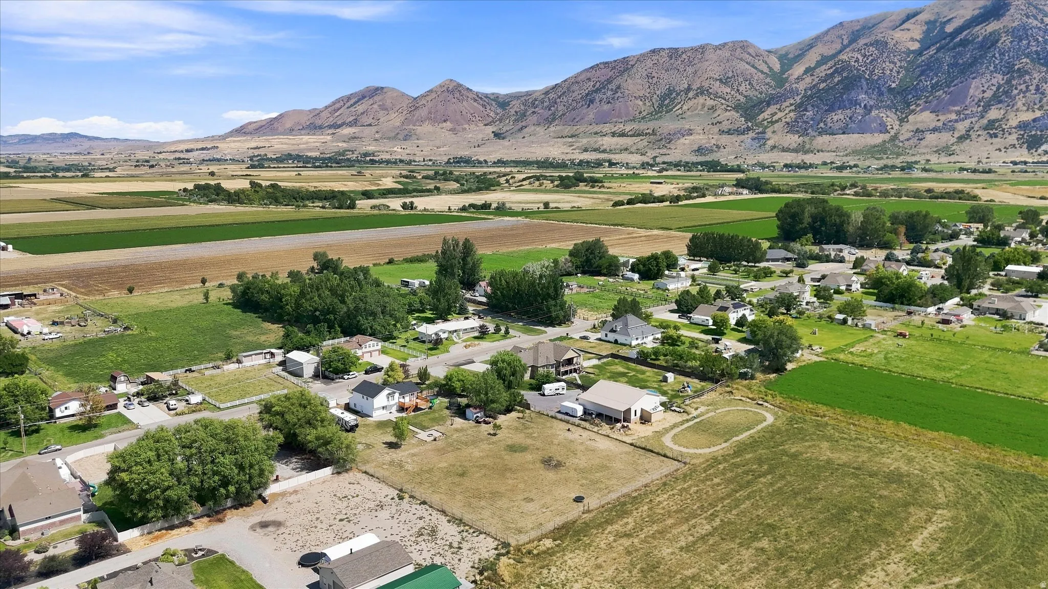 Expansive rural landscape featuring distant mountains, cultivated fields, and scattered residential properties