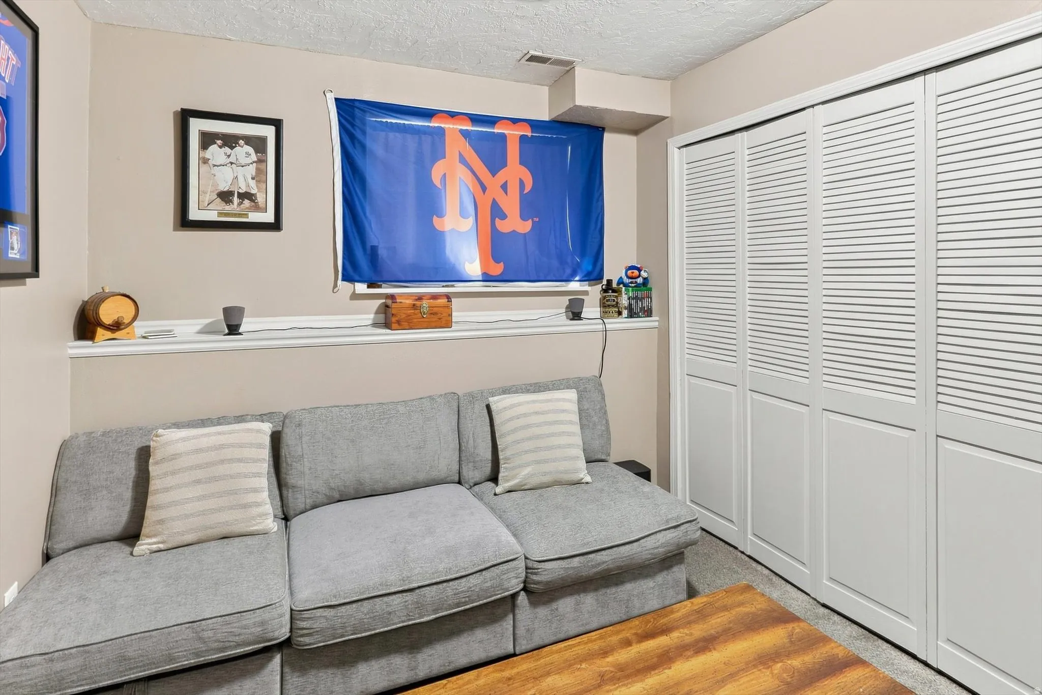 White louvered bi-fold closet doors, carpeted flooring, and a display ledge feature in this room