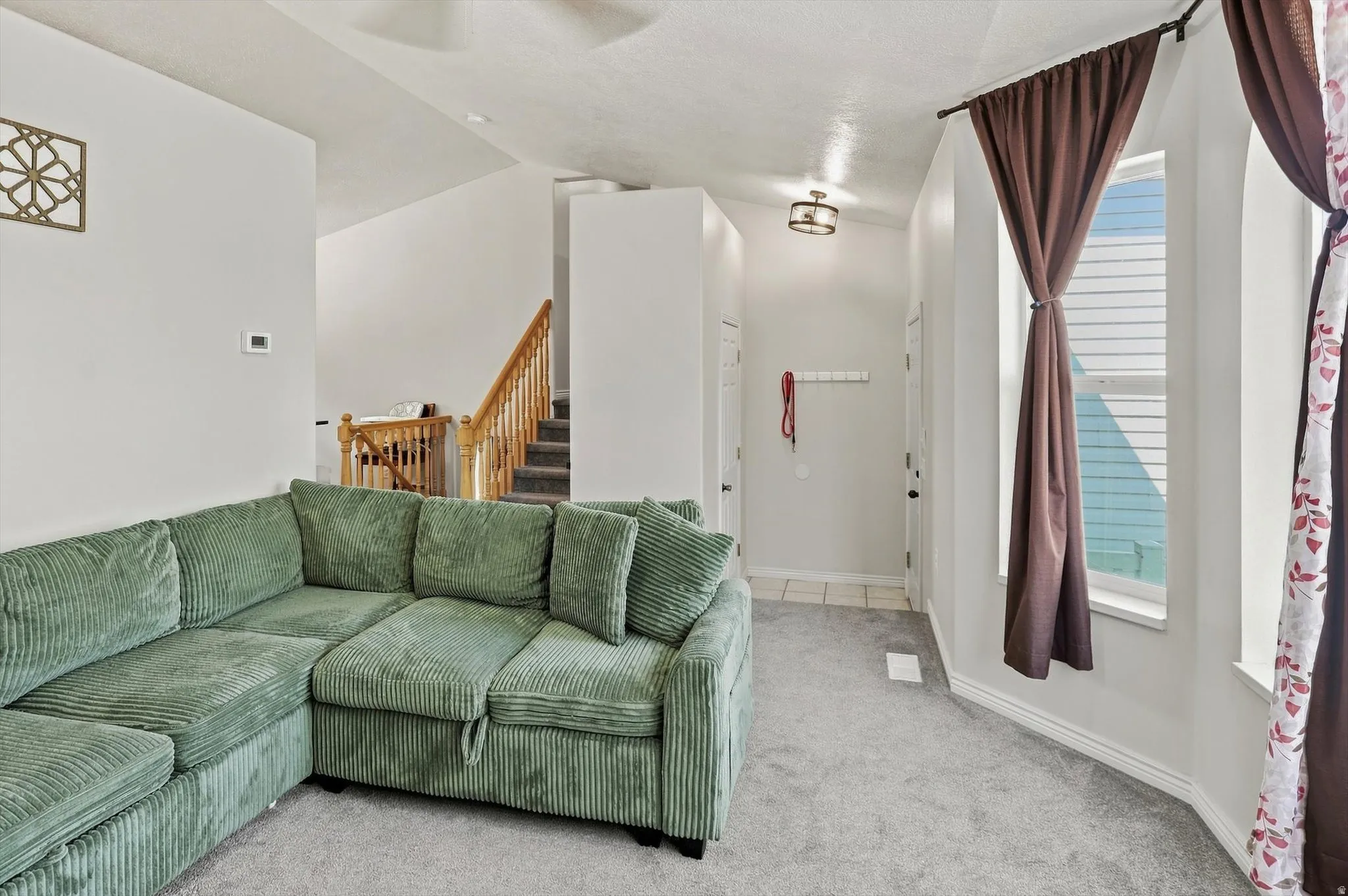 Carpet flooring, staircase with wooden handrail, tile flooring, recessed window, and flush mount lighting