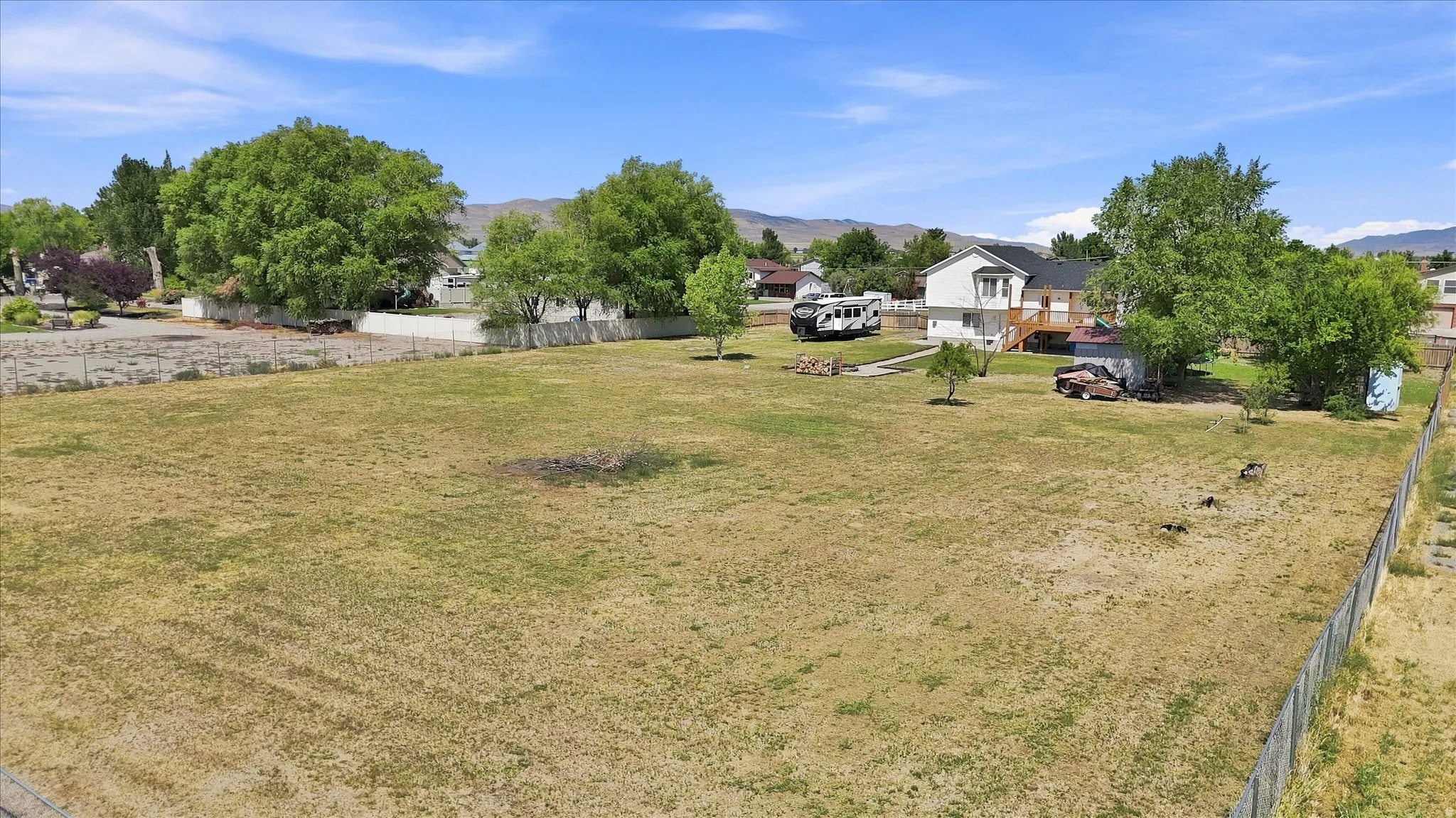 Expansive lot featuring a fence line, mature trees, and a distant mountain backdrop