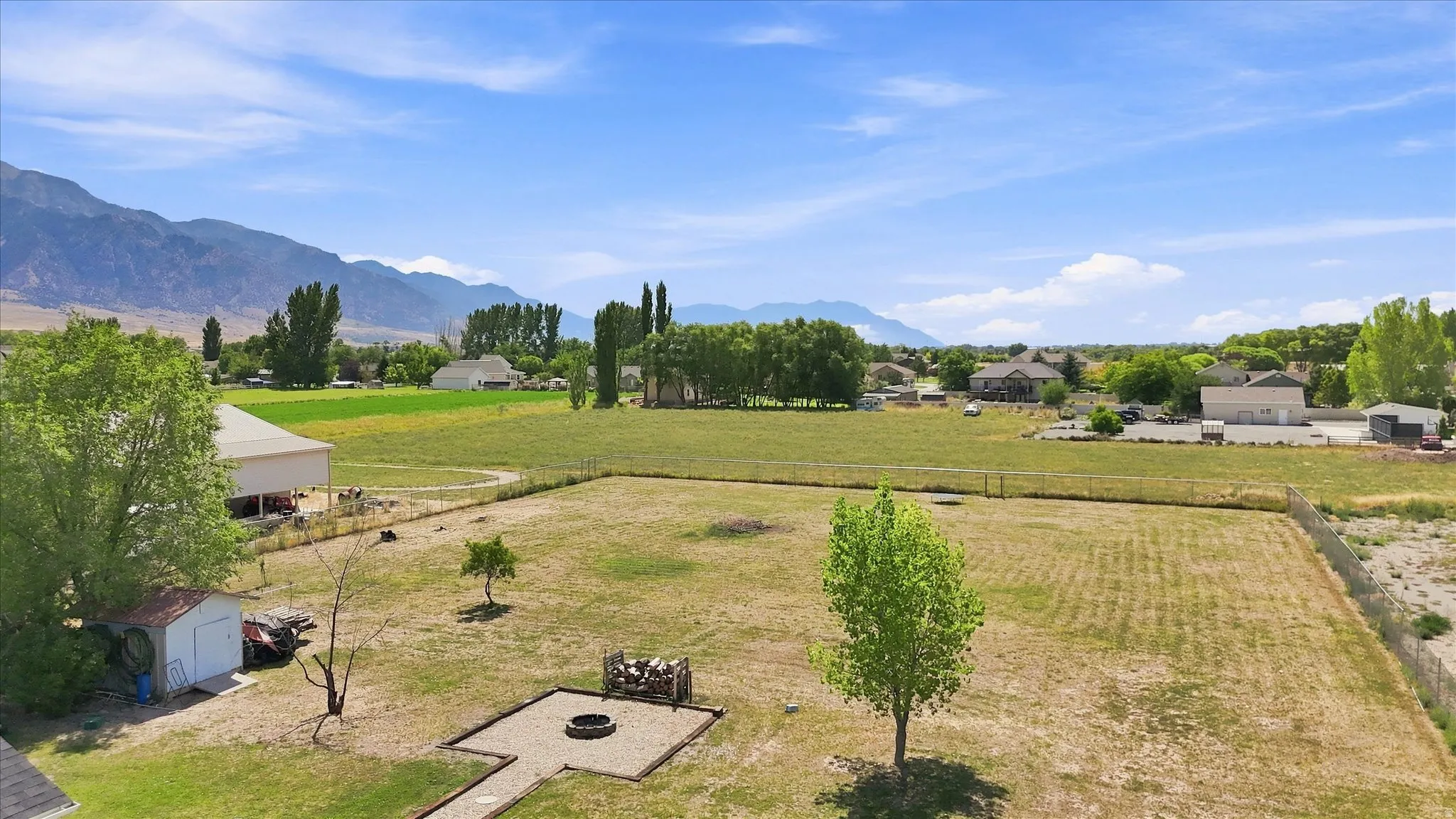 Expansive backyard featuring a fire pit, storage shed, and mature trees