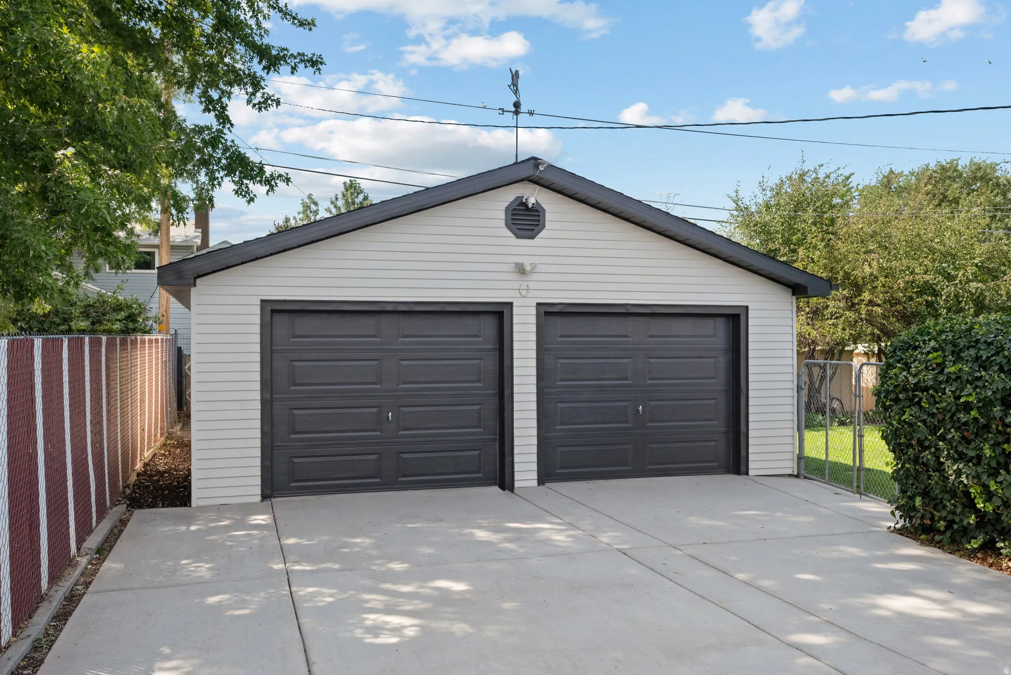 Two-car garage with light-colored siding, dark-colored garage doors, and a concrete driveway