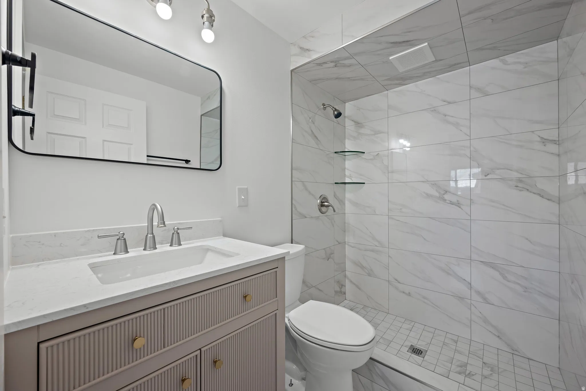 Vanity with a light-toned countertop, under-mount sink, and brushed nickel faucet
