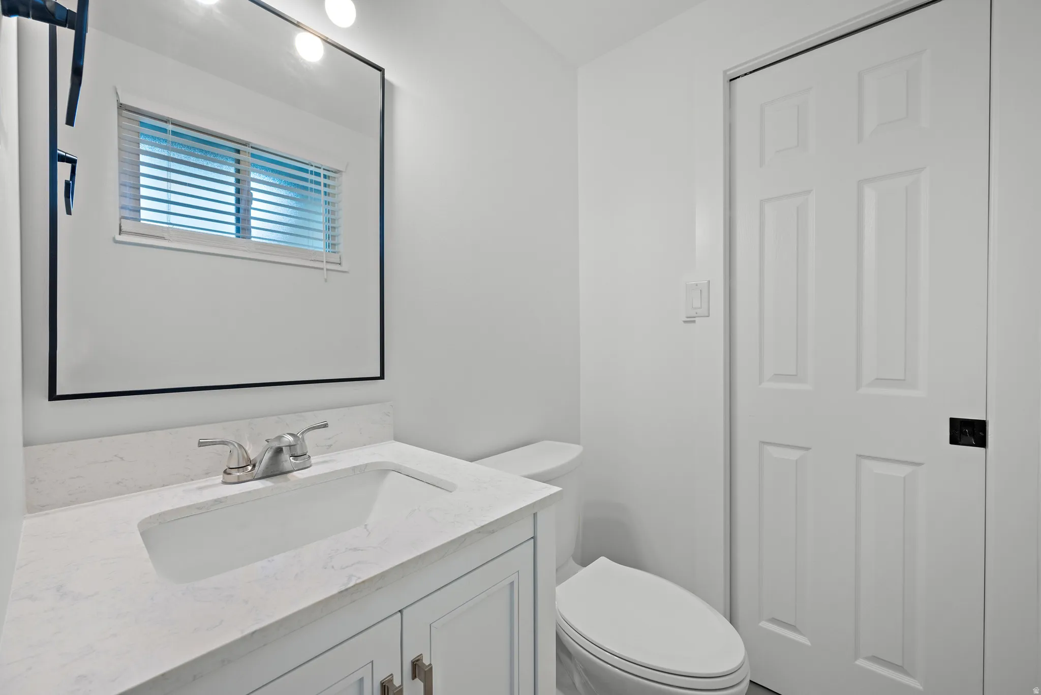Vanity with white shaker-style cabinetry, white countertop, and integrated sink