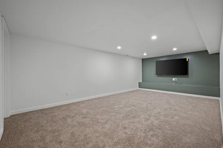 Recessed lighting, carpeted flooring, and a built-in media console