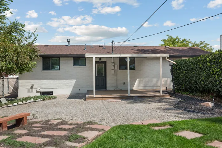 Rear exterior featuring a covered patio, brick facade, and gravel landscaping
