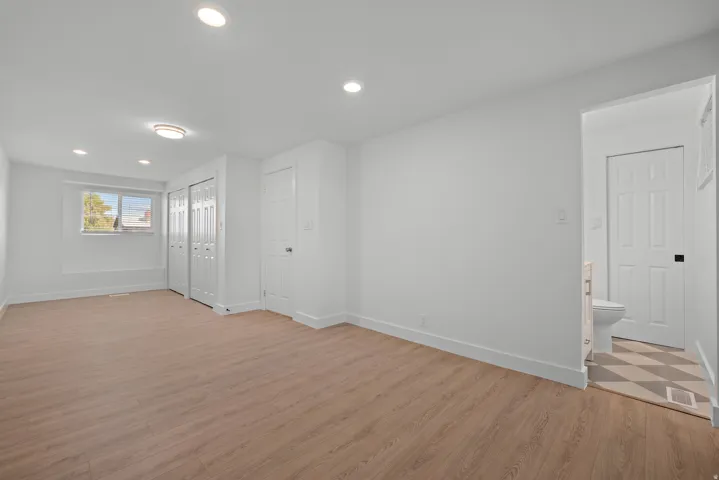 Recessed lighting, wood-finish flooring, and white bi-fold closet doors