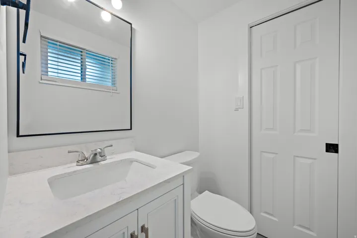 Vanity with white shaker-style cabinetry, white countertop, and integrated sink