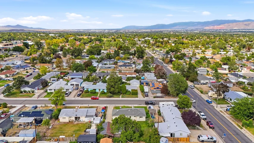 Residential neighborhood with mature trees and paved streets, framed by distant mountains