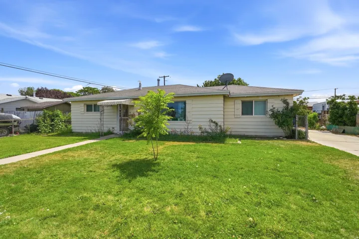 Expansive green lawn with a concrete walkway, single-story residence, and a paved driveway