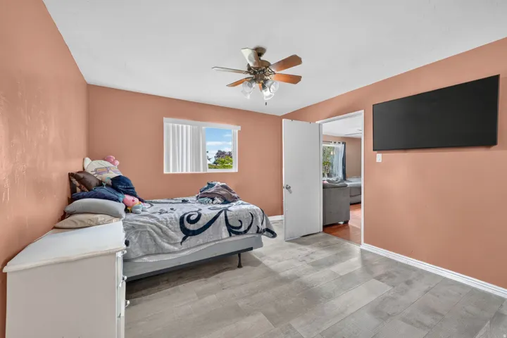 Wood-finish flooring, ceiling fan, and window with blinds