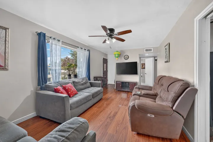 Wood-finish flooring throughout, ceiling fan with integrated lighting, and a large window providing natural illumination