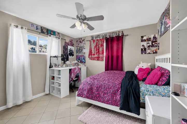 Ceiling fan with light fixture, window with drapes, tile flooring, and built-in shelving