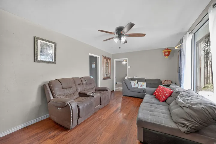 Wood-finish flooring throughout, complemented by light gray wall tones and a ceiling fan with integrated lighting
