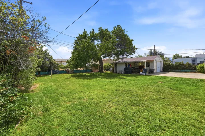 Expansive green lawn with mature trees and a detached garage featuring a covered patio