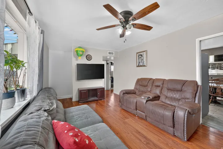 Warm wood-finish flooring, recessed lighting, and a ceiling fan with integrated lighting