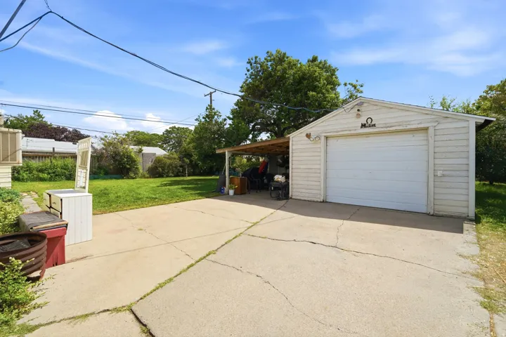 Detached garage featuring a white overhead door and covered carport