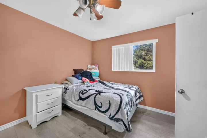 Recessed window with horizontal blinds, wood-finish flooring, and a ceiling fan with integrated lighting