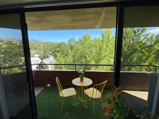 Balcony with brick half-wall, black metal railing, and turf flooring