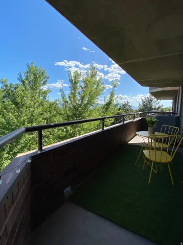 Private balcony with a concrete floor, dark brick half-wall, and a black metal railing