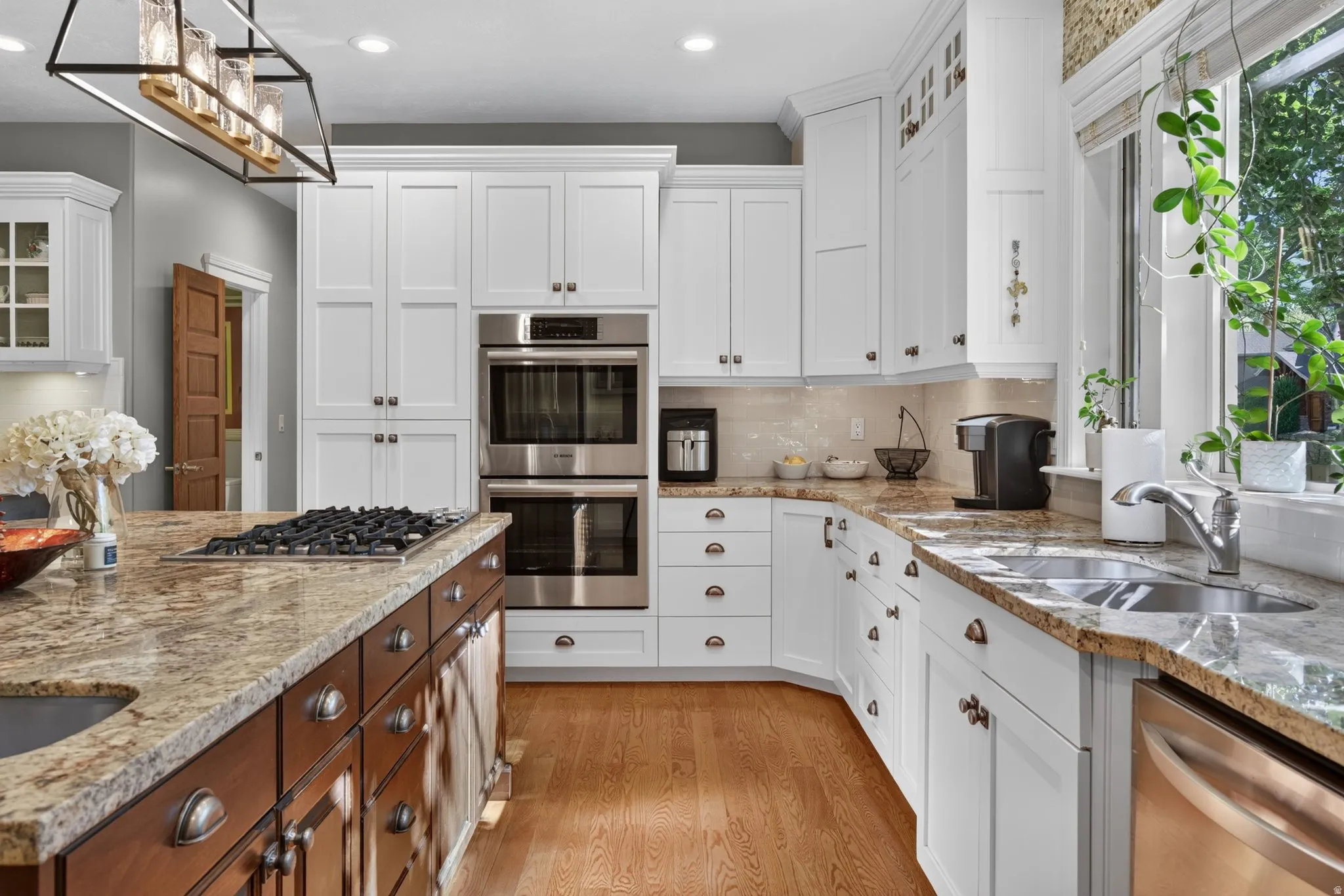 Kitchen featuring white cabinetry, stone countertops, stainless steel appliances, a center island with a gas cooktop, and wood-finish flooring