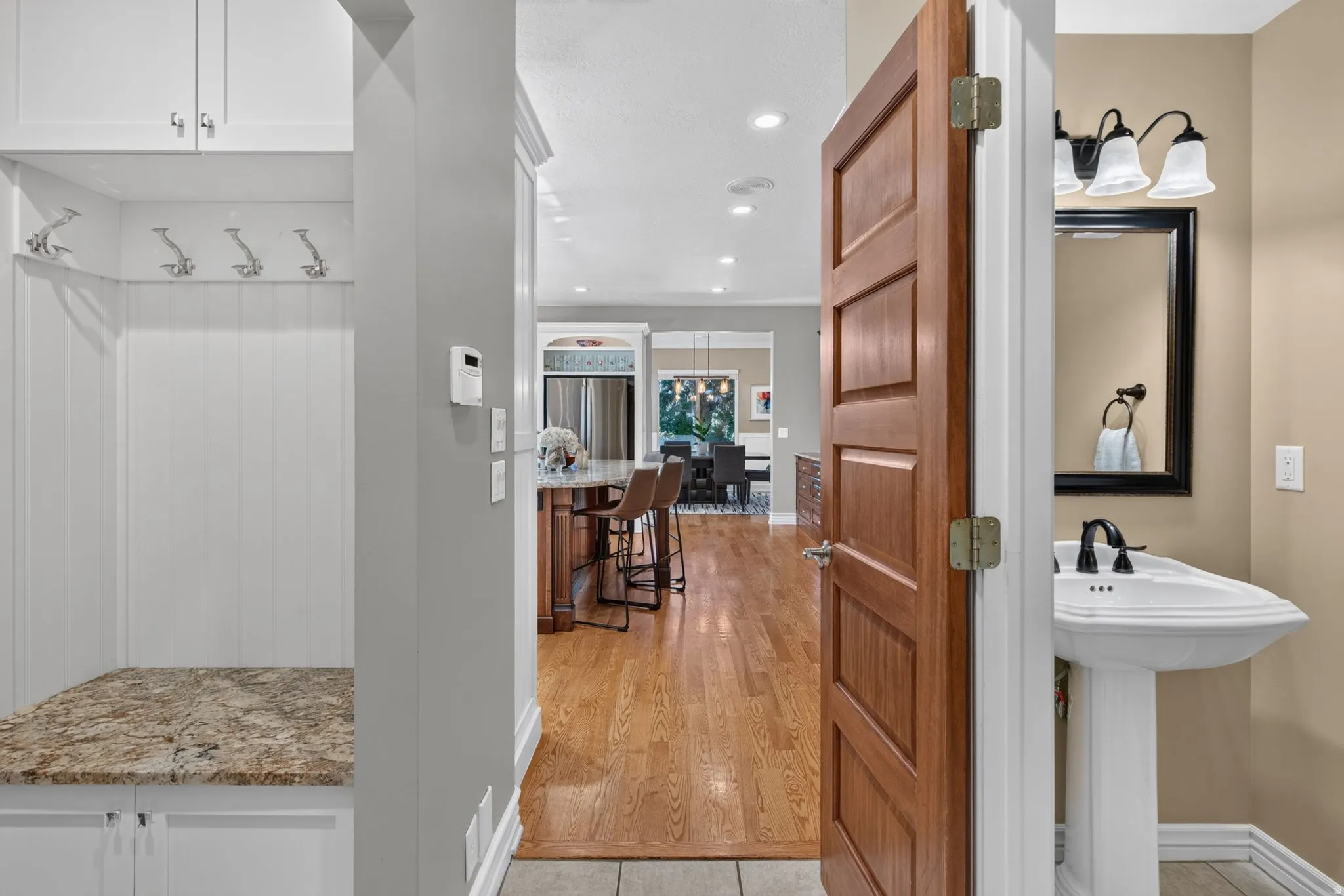 Built-in mudroom bench with granite-style countertop, white cabinetry, and wall-mounted hooks