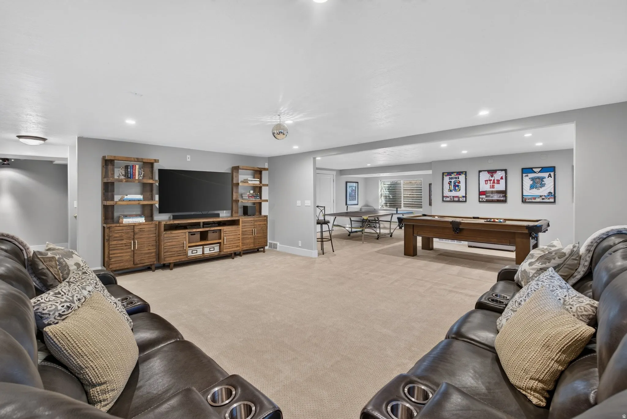 Expansive recreational area featuring recessed lighting, a built-in media console with shelving, and light neutral carpeting