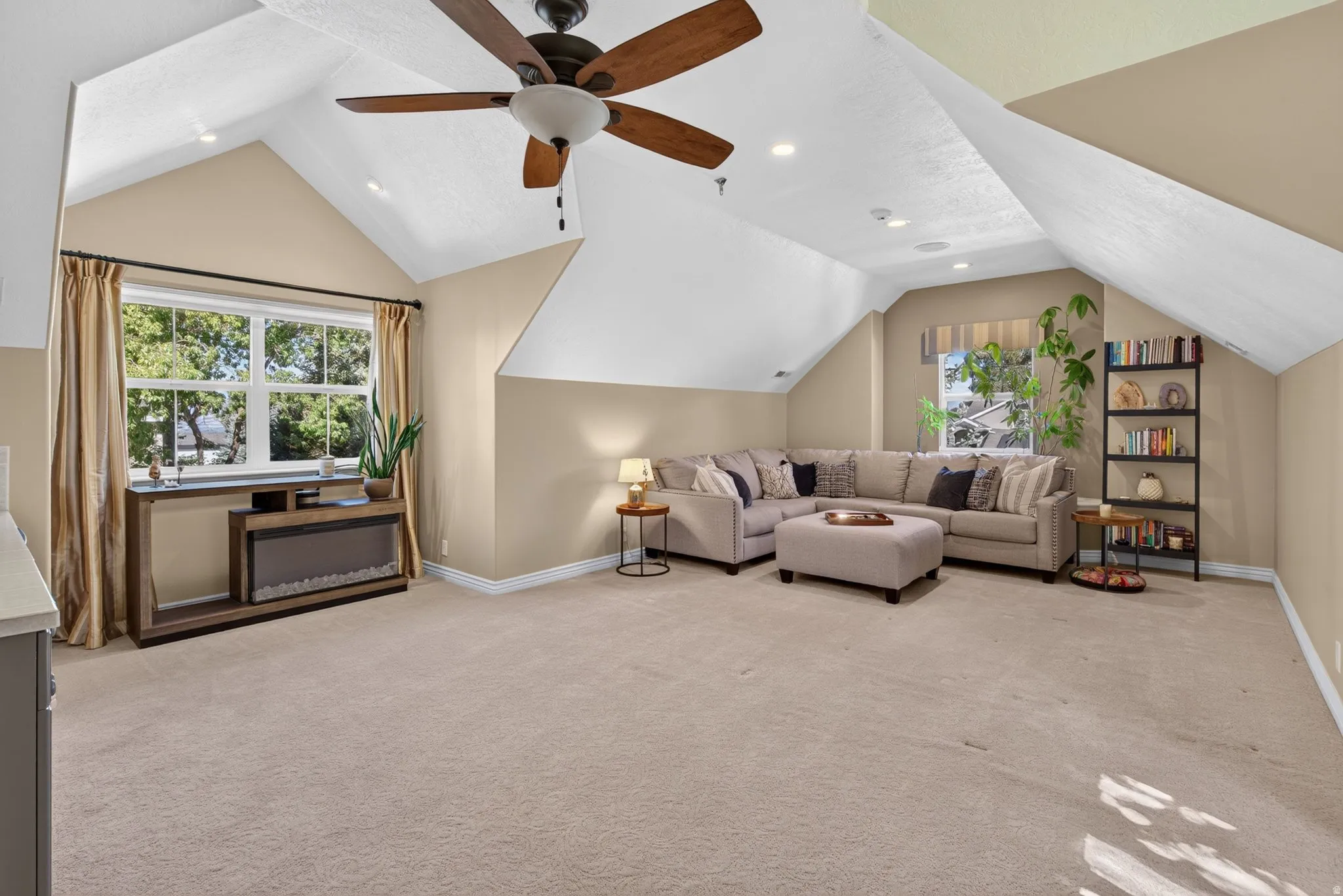Spacious attic room with vaulted ceilings, ceiling fan, and recessed lighting