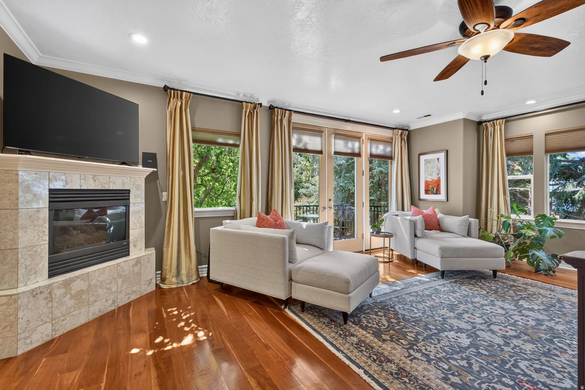 Hardwood flooring, recessed lighting, ceiling fan, crown molding, and tiled fireplace