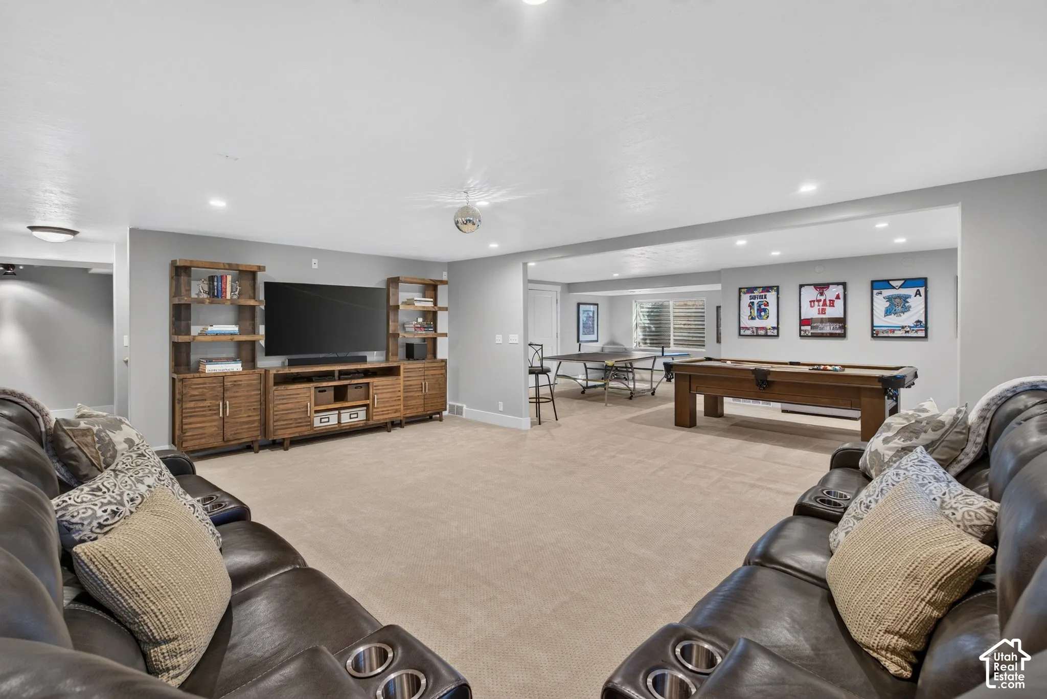 Expansive recreational area featuring recessed lighting, a built-in media console with shelving, and light neutral carpeting
