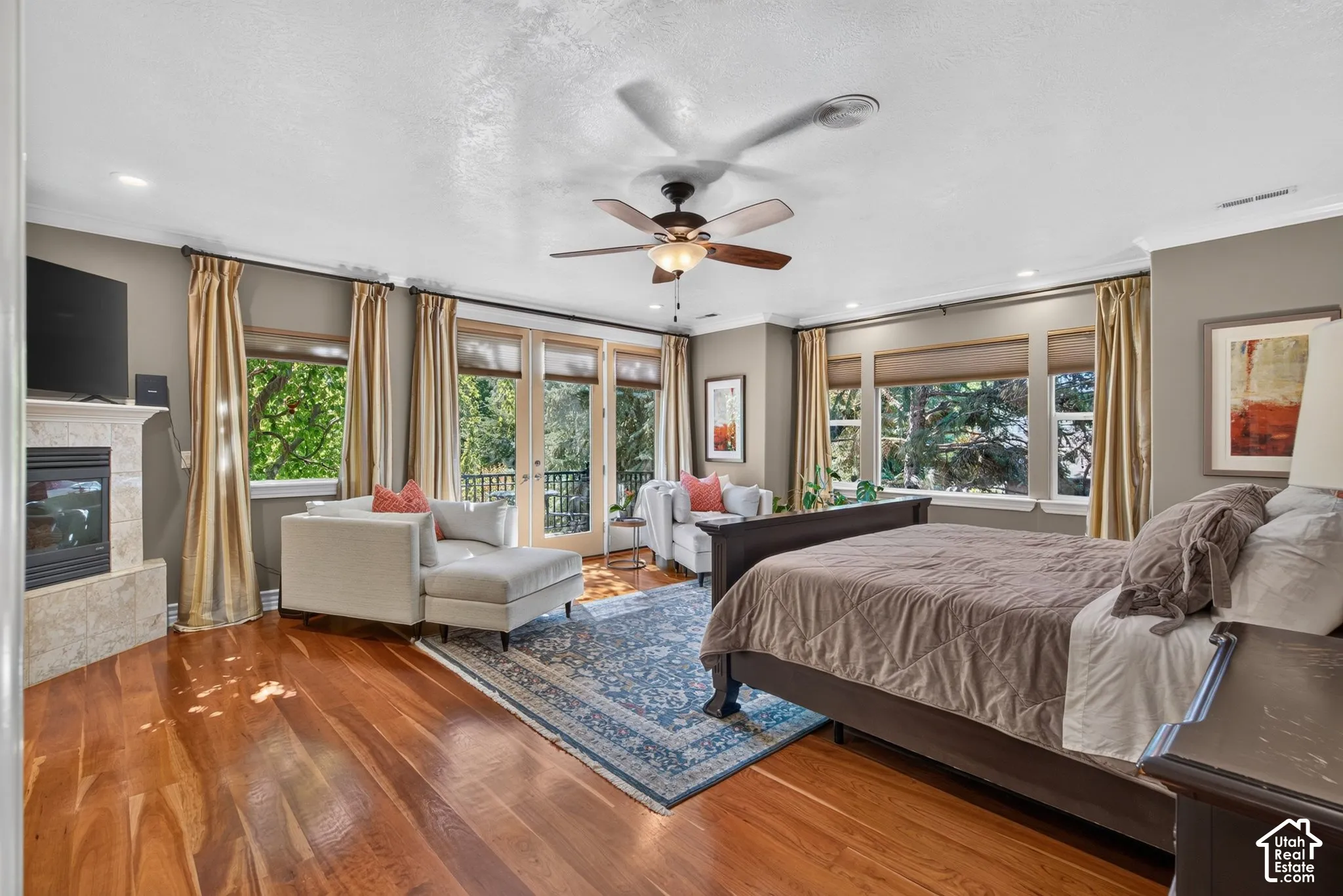 Hardwood flooring, recessed lighting, ceiling fan, fireplace with stone surround, and French doors