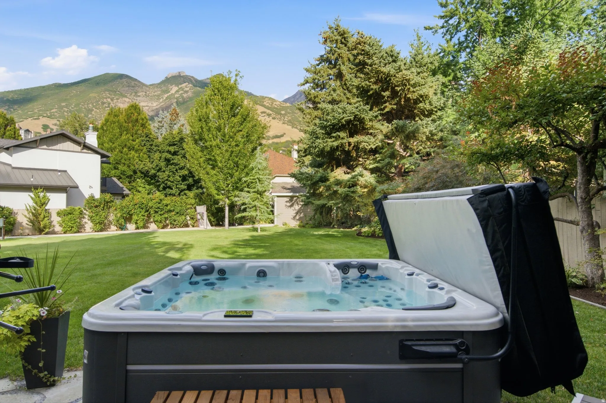 Expansive outdoor spa with a hinged cover, set on a paver patio