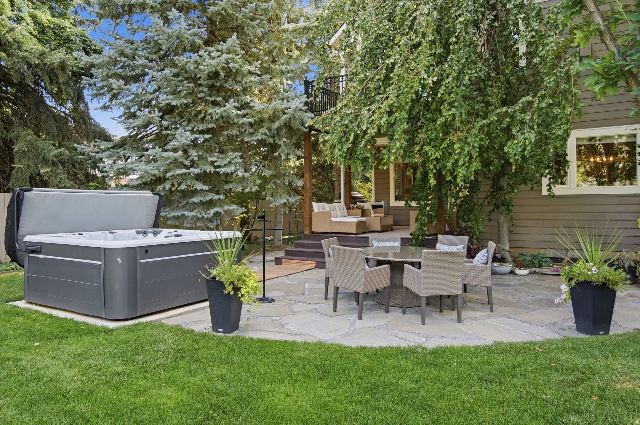 Manicured lawn, hot tub, flagstone patio, multi-level deck, and exterior siding