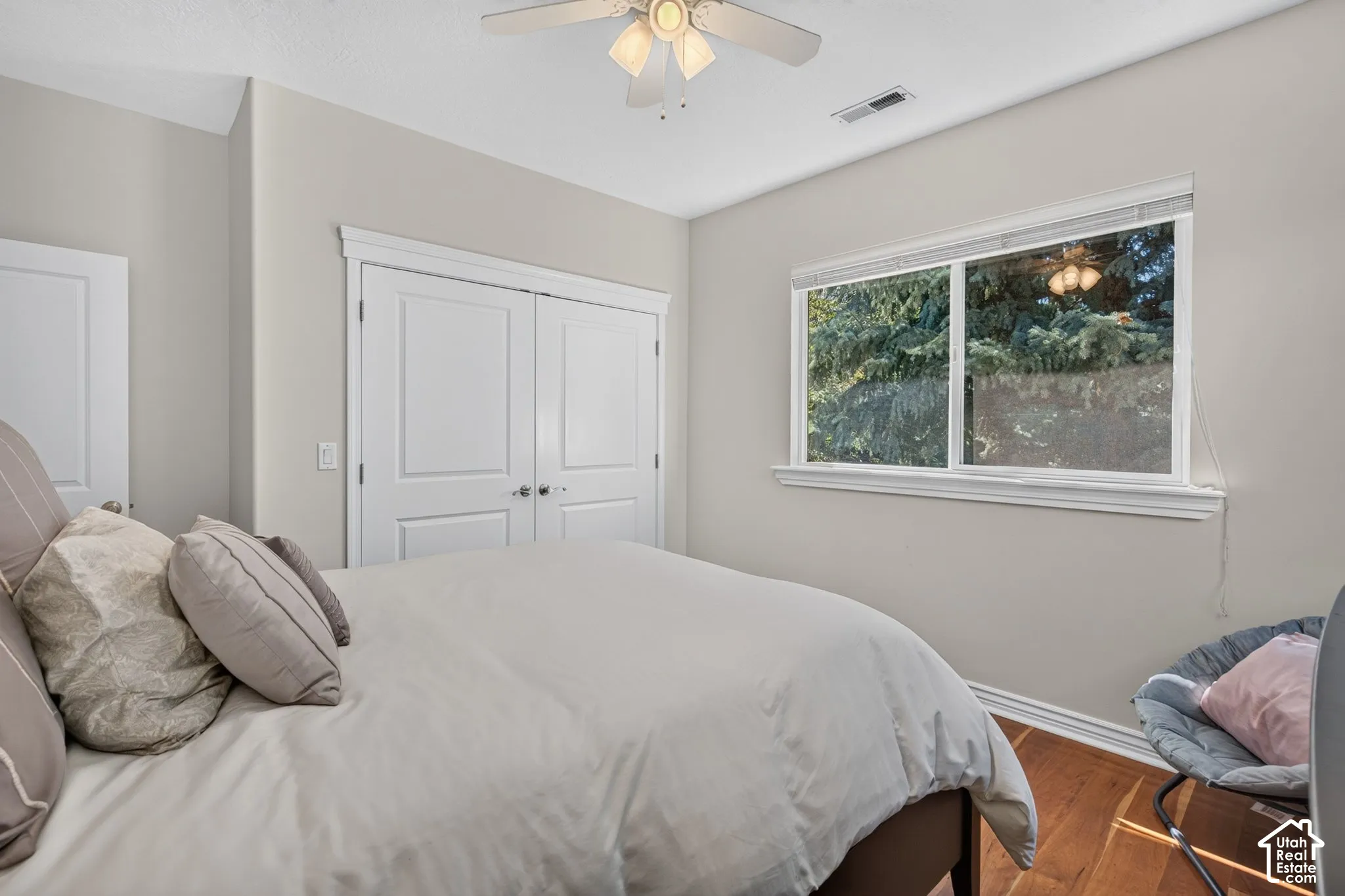 Wood-finish flooring, white trim, a ceiling fan, and a double-door closet