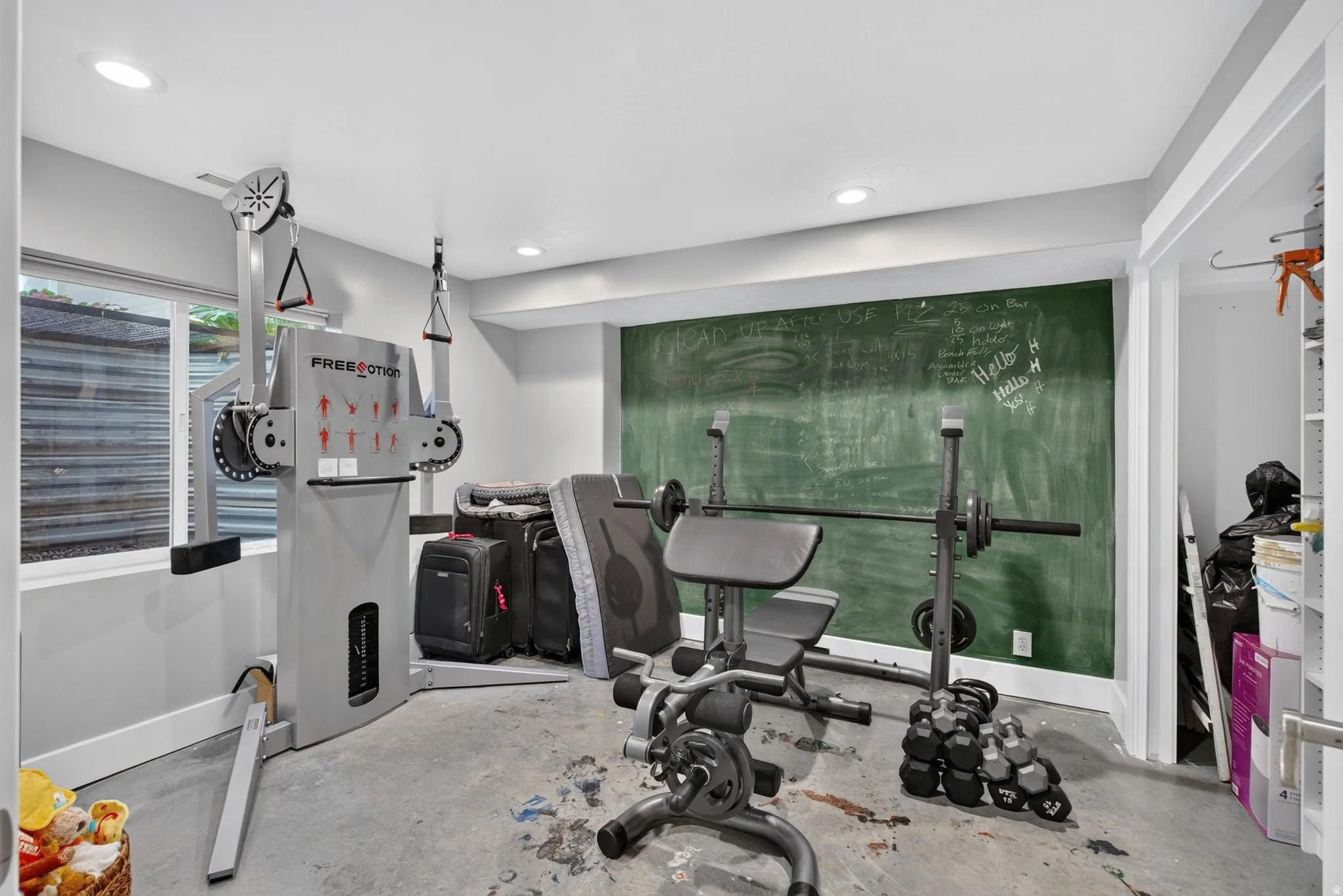 Recessed lighting, chalkboard accent wall, window, and concrete flooring