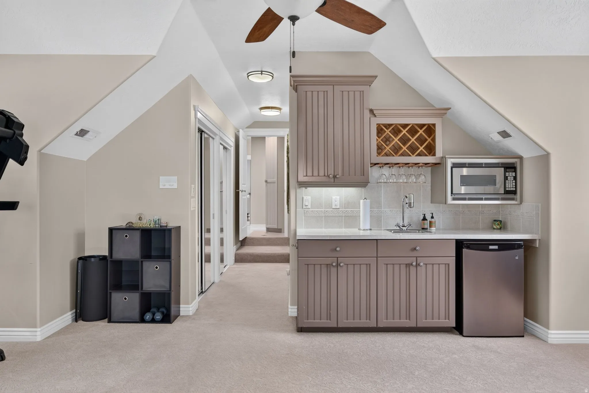 Integrated wet bar featuring a built-in microwave, under-counter refrigerator, and wine rack