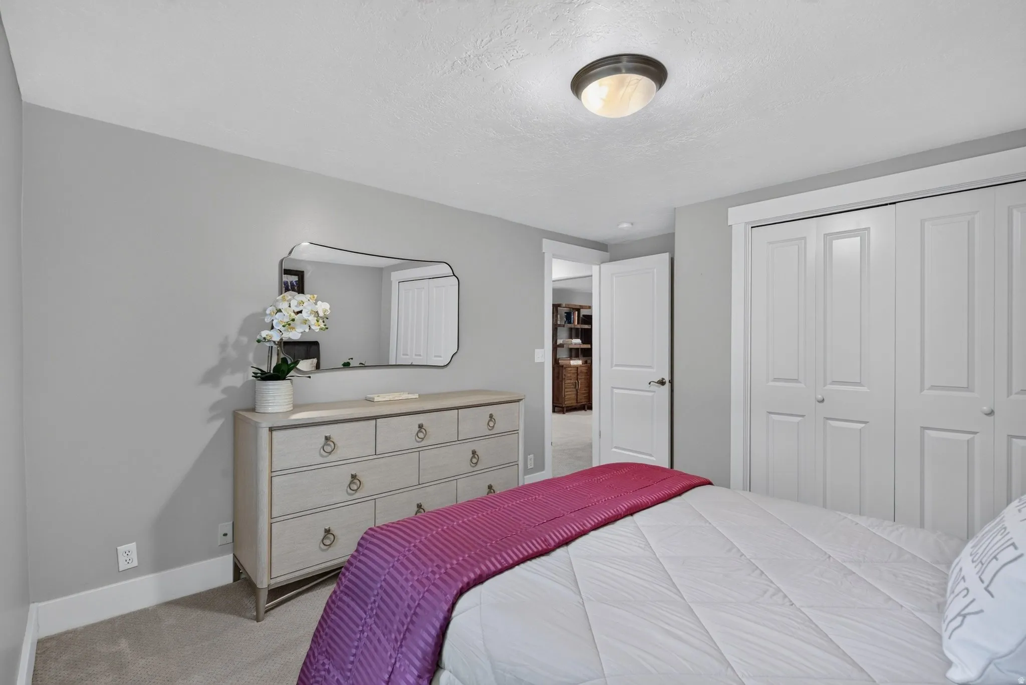 Carpeted flooring, neutral wall color, white trim, flush mount ceiling light, and bi-fold closet doors