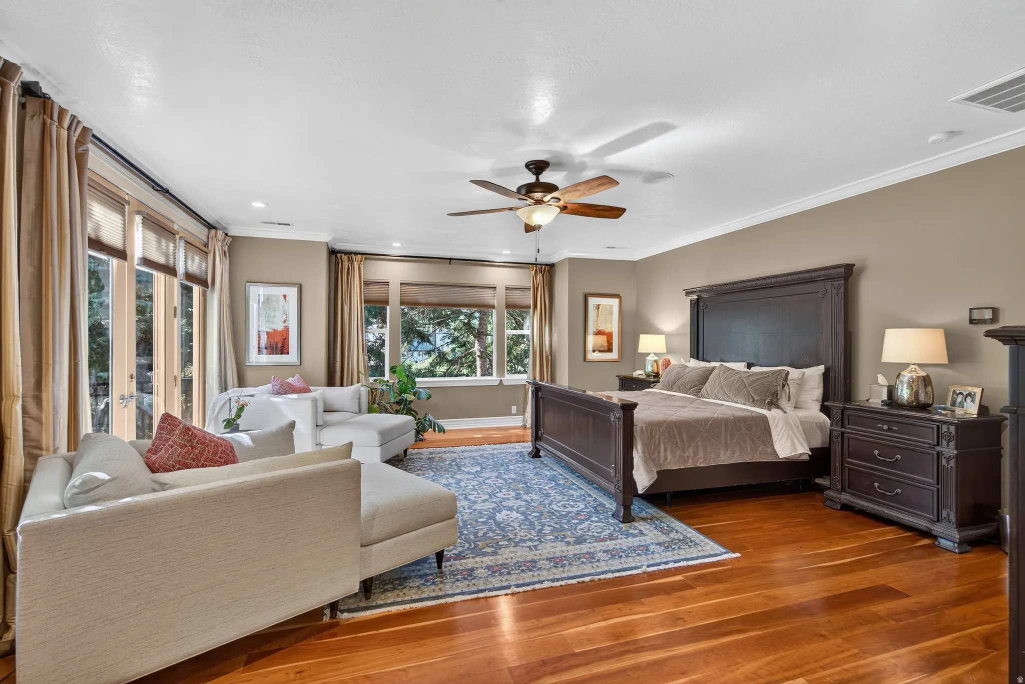 Hardwood flooring, crown molding, ceiling fan, and multiple windows