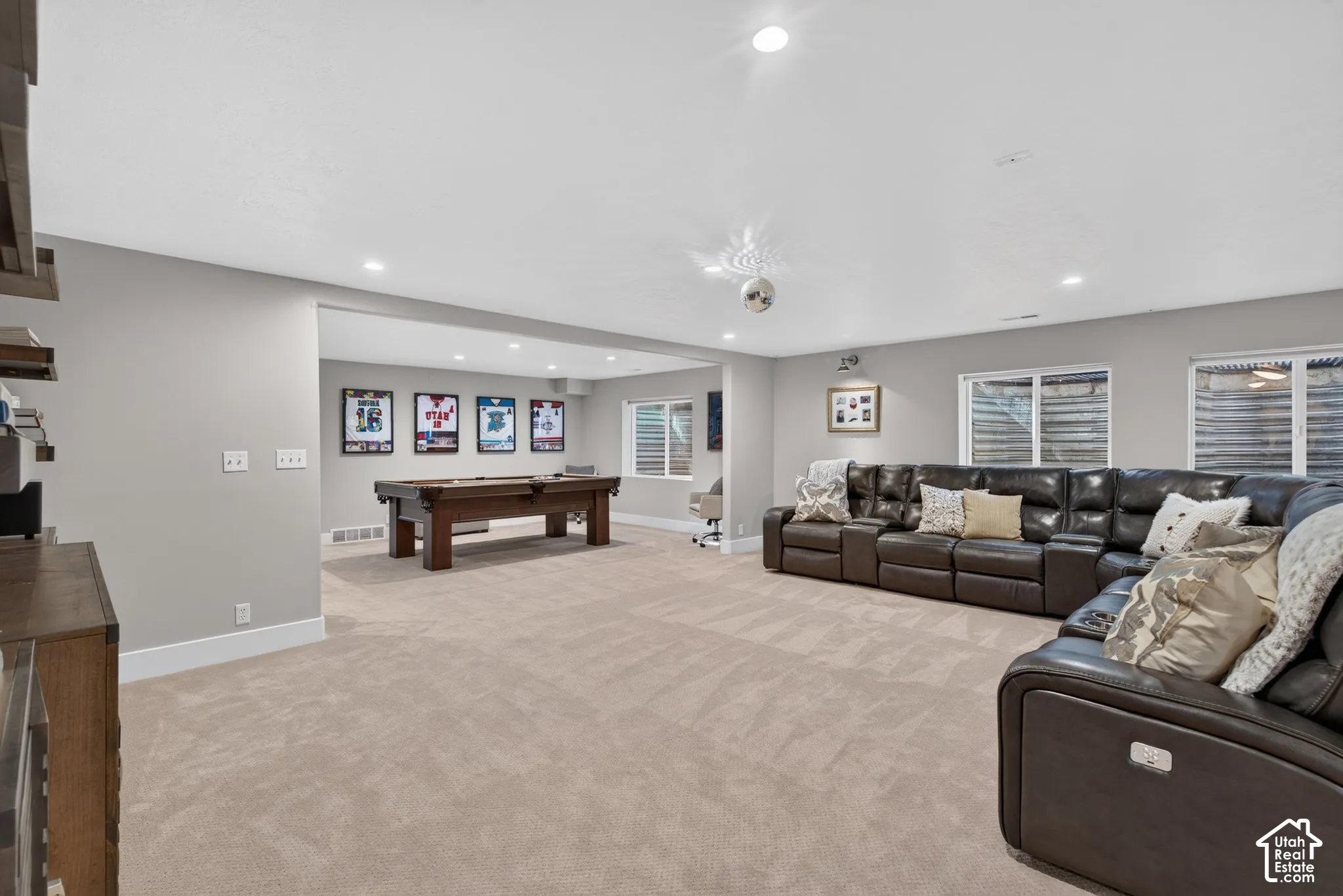 Recessed lighting illuminates the expansive carpeted flooring, complemented by multiple wall-mounted windows