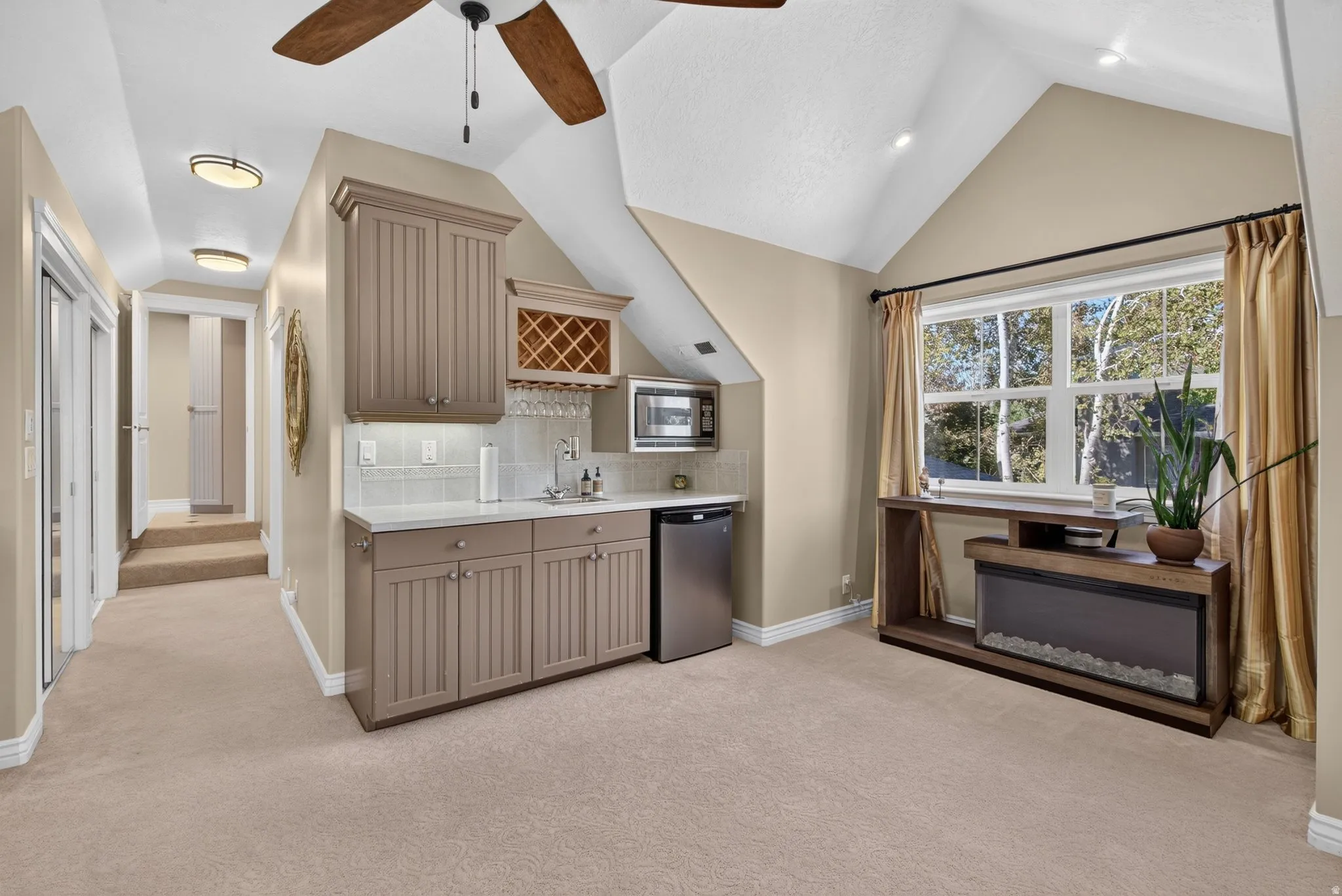 Built-in wet bar with wood-finish cabinetry, under-cabinet lighting, and subway tile backsplash