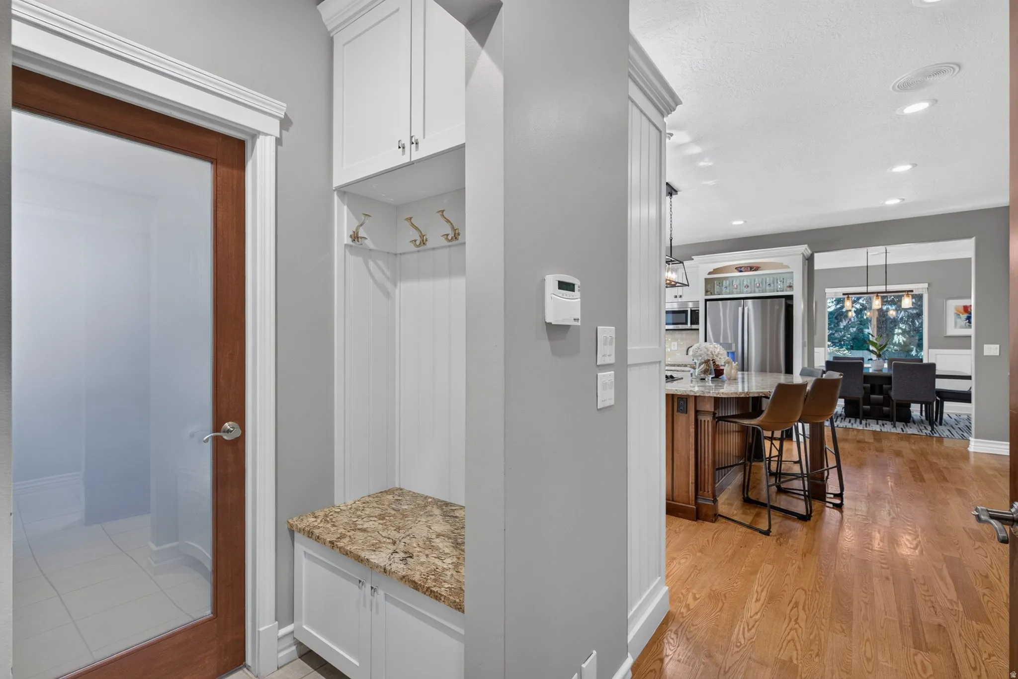 Built-in mudroom bench with granite countertop, white cabinetry, and wall hooks
