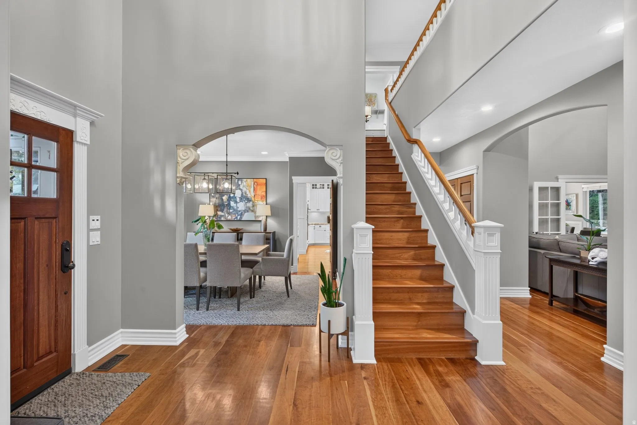 Hardwood flooring throughout, a grand staircase with white balusters, and arched doorways define this entry
