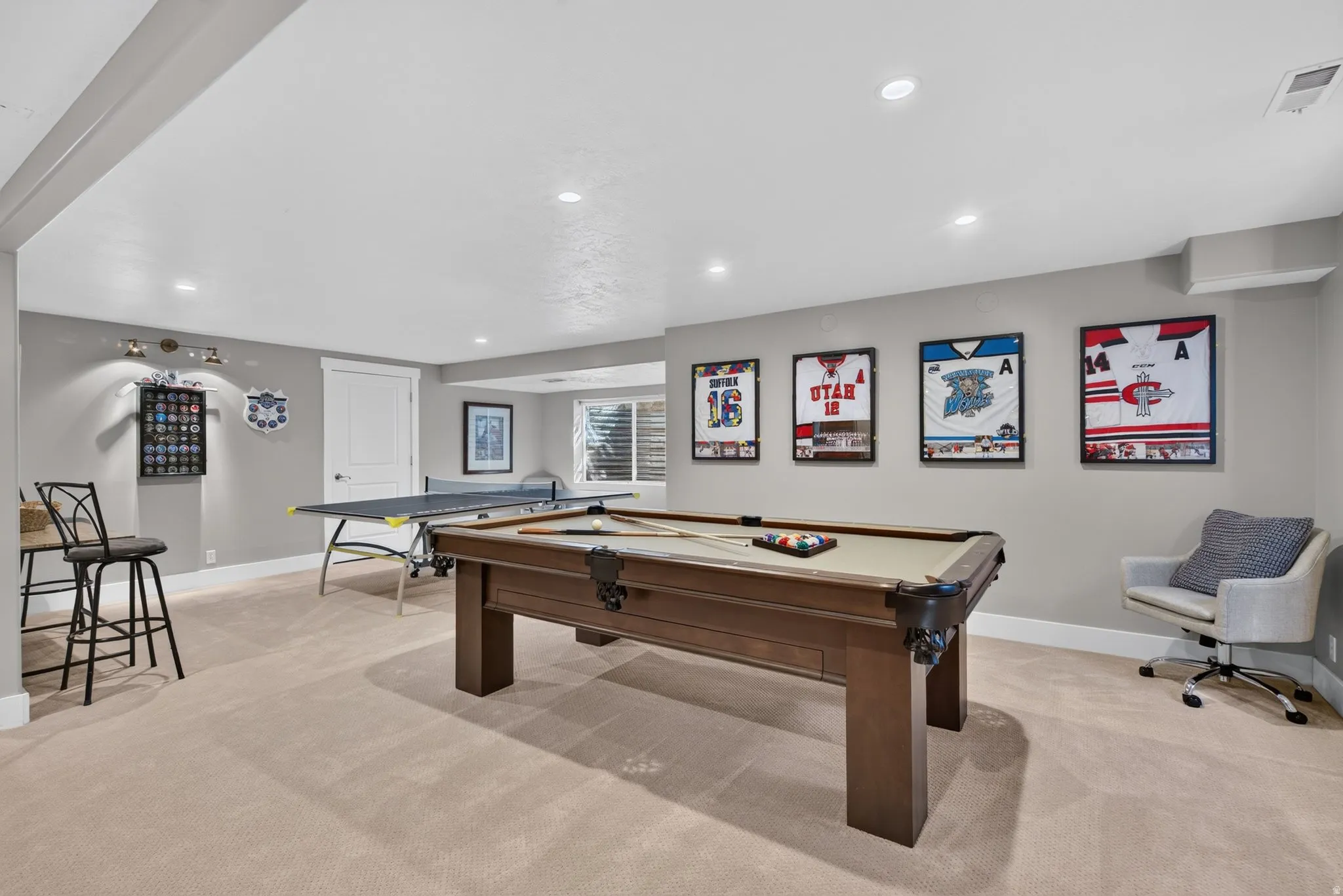 Recessed lighting illuminating the entertainment space with light gray walls, white trim, and light-toned carpeting