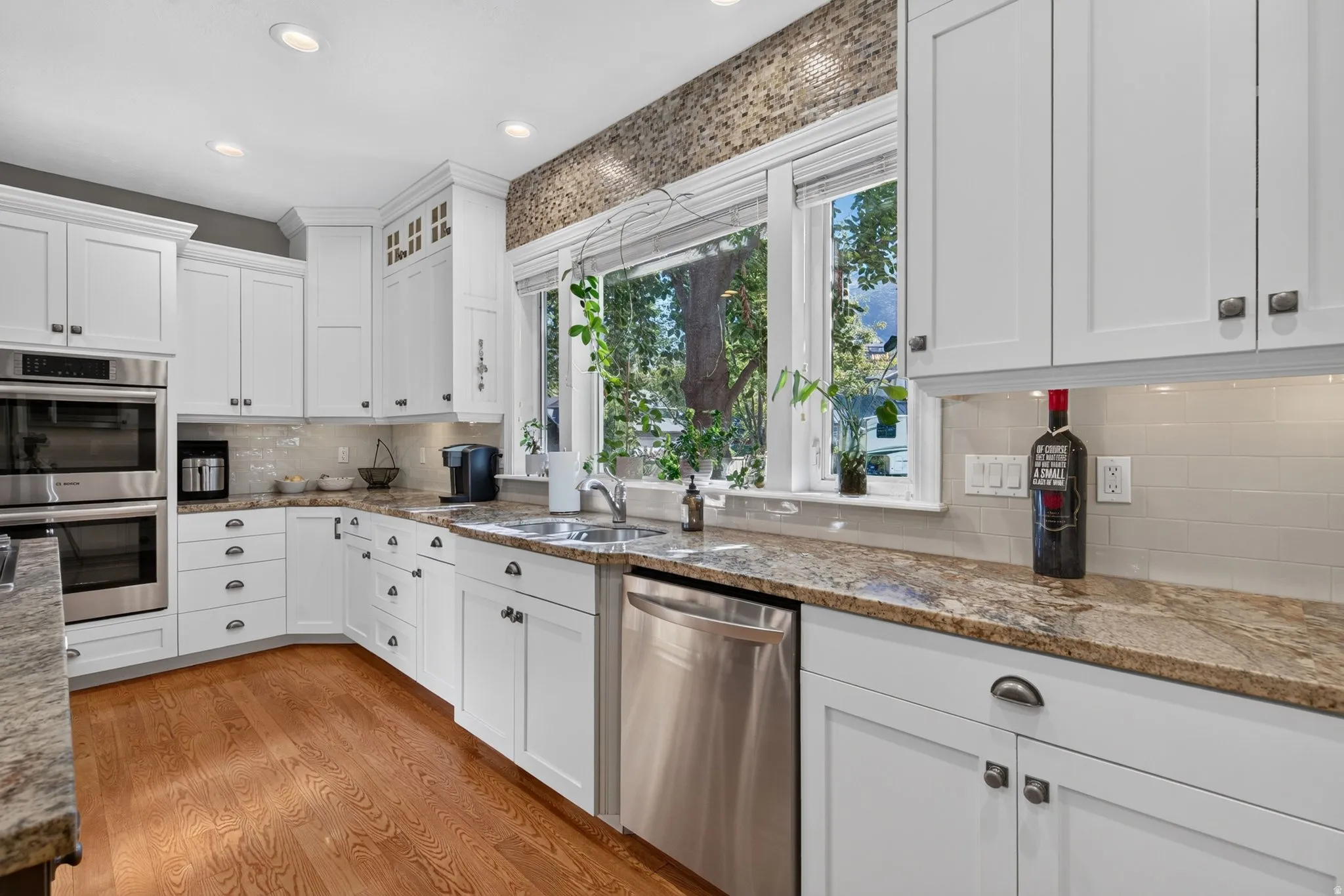 White cabinetry with dark hardware, stone countertops, stainless steel appliances, wood-finish flooring, and recessed lighting