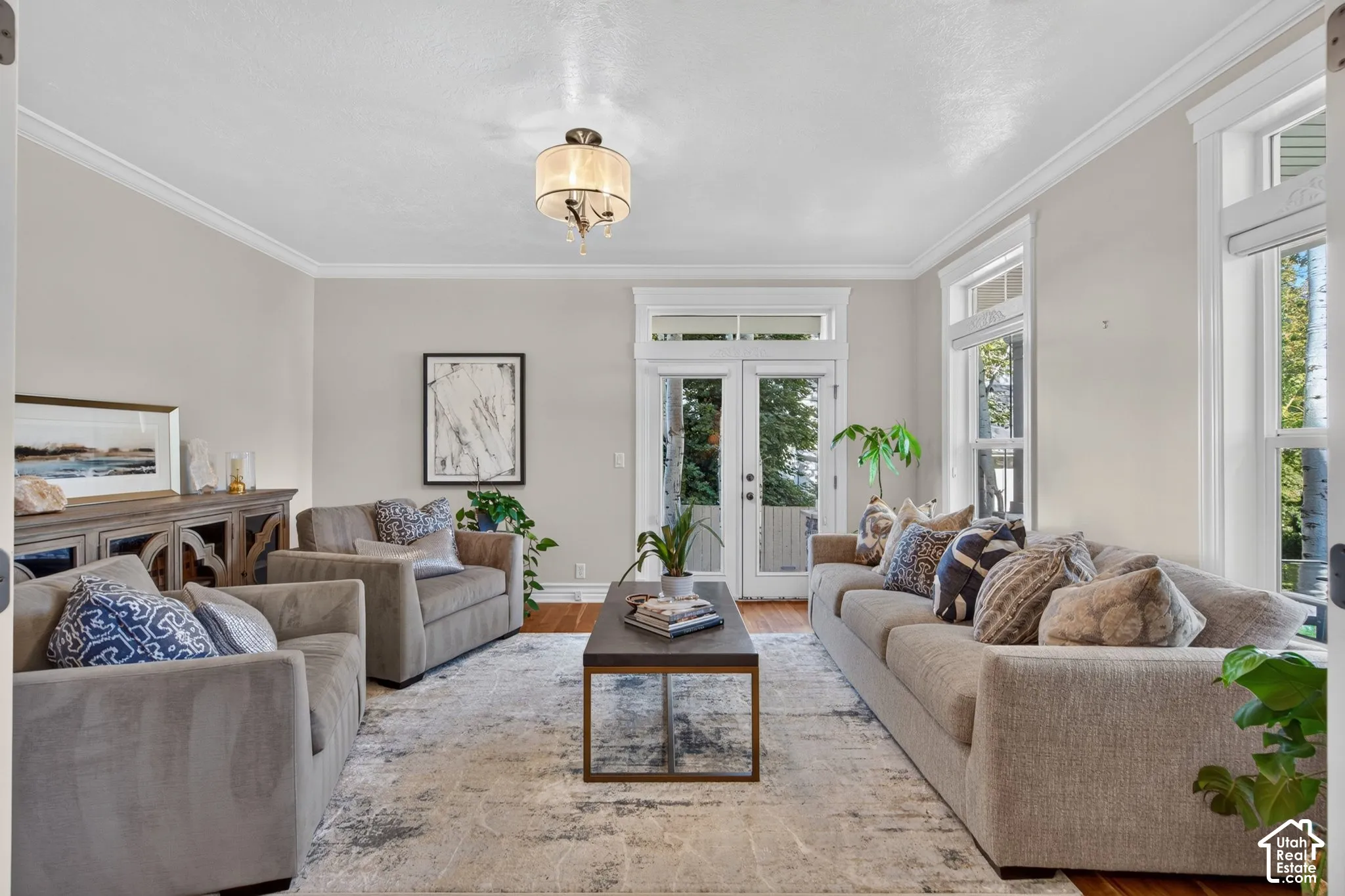 Hardwood flooring, crown molding, double French doors, large windows, and a chandelier with a drum shade
