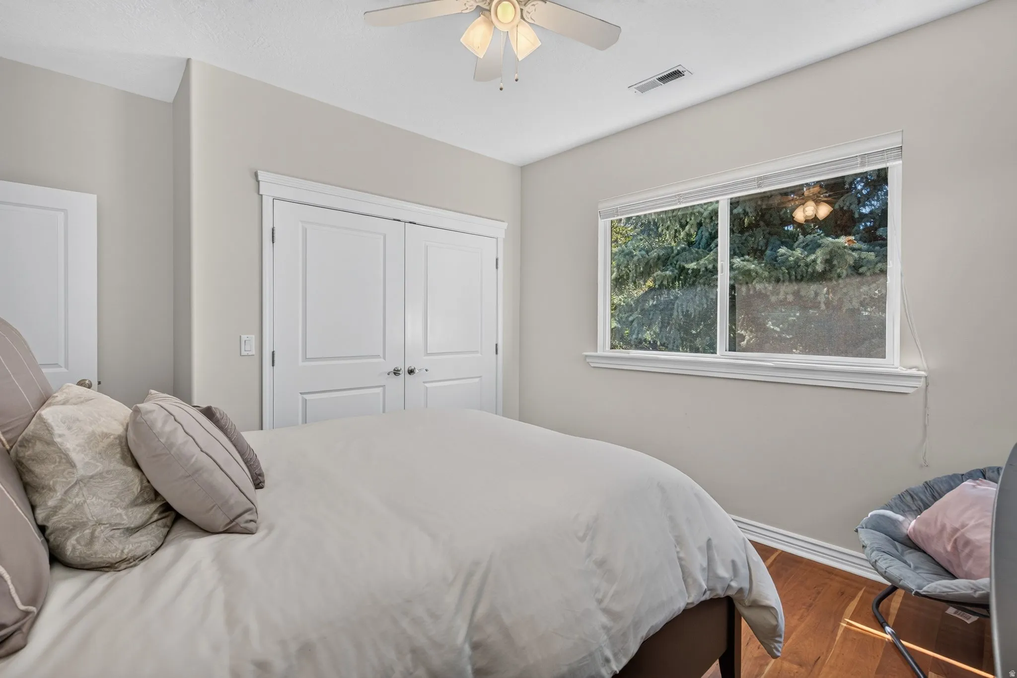 Wood-finish flooring, white trim, a ceiling fan, and a double-door closet